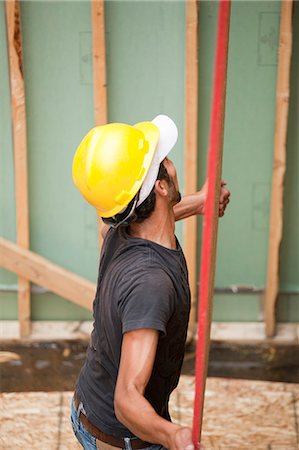 simsearch:6105-05396204,k - Hispanic carpenter lifting sheathing at a house under construction Stock Photo - Premium Royalty-Free, Code: 6105-05396195