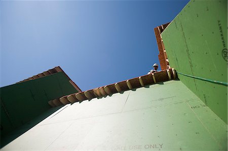 Hispanic carpenter hanging over roof edge at a house under construction Stock Photo - Premium Royalty-Free, Code: 6105-05396247