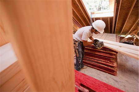 simsearch:6105-05396204,k - Hispanic carpenter using a circular saw on a rafter at a house under construction Stock Photo - Premium Royalty-Free, Code: 6105-05396257