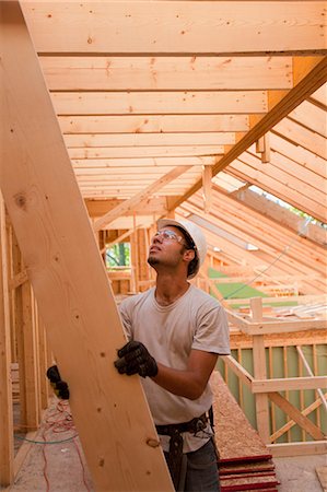 Hispanic carpenter passing up a rafter to roof at a house under construction Stock Photo - Premium Royalty-Free, Code: 6105-05396263