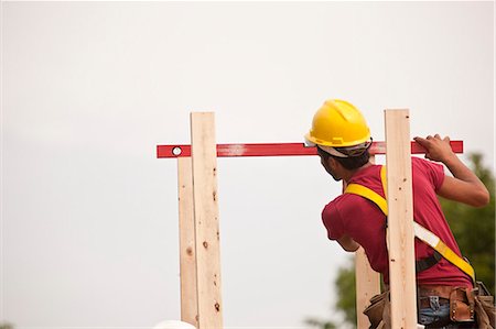 simsearch:6105-05396204,k - Hispanic carpenter measuring chimney posts with a level at a house under construction Stock Photo - Premium Royalty-Free, Code: 6105-05396267