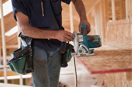 Charpentier hispanique à l'aide d'une scie circulaire sur le panneau de toit sur une maison en construction Photographie de stock - Premium Libres de Droits, Code: 6105-05396273