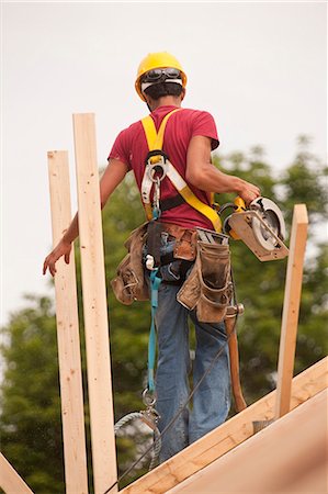 Hispanic carpenter using a circular saw on the roof at a house under construction Foto de stock - Sin royalties Premium, Código: 6105-05396270