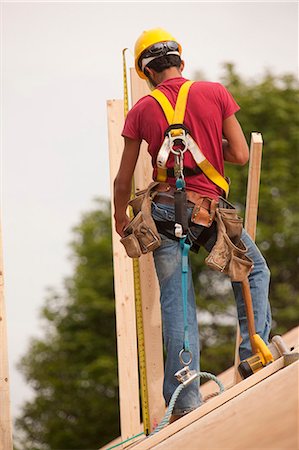simsearch:6105-05396204,k - Hispanic carpenter measuring a board on the roof of a house under construction Stock Photo - Premium Royalty-Free, Code: 6105-05396294
