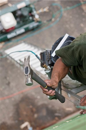 Hispanic carpenter climbing ladder with hammer and nail gun at a house under construction Stock Photo - Premium Royalty-Free, Code: 6105-05396209