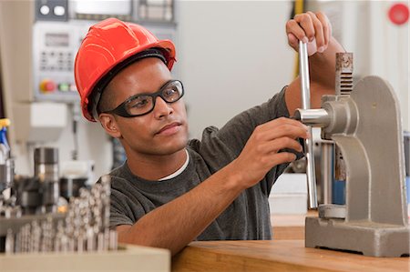 simsearch:6105-05953759,k - Engineering student operating a manual bench top C-frame press machine Stock Photo - Premium Royalty-Free, Code: 6105-05396360