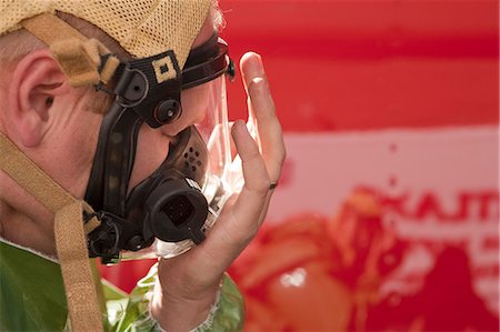 simsearch:6105-06703091,k - HazMat firefighter putting on mask and checking the seal Stock Photo - Premium Royalty-Free, Code: 6105-05396481