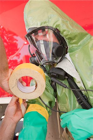 simsearch:6105-06703091,k - HazMat firefighter assisting his colleague in taping protective gloves Stock Photo - Premium Royalty-Free, Code: 6105-05396487