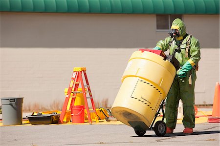 HazMat firefighter pushing a salvage drum Stock Photo - Premium Royalty-Free, Code: 6105-05396490