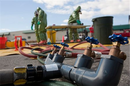 simsearch:6105-06703091,k - Water distribution manifold in HazMat decontamination area with HazMat firefighters in the background Stock Photo - Premium Royalty-Free, Code: 6105-05396524