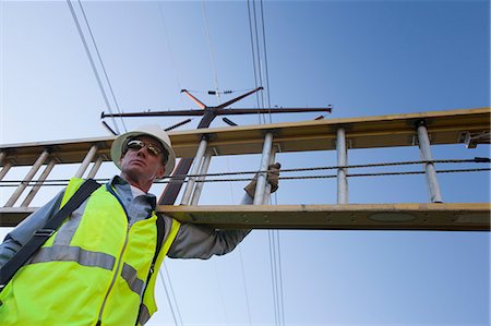 simsearch:6105-05396624,k - Engineer carrying a ladder to install equipment on power poles Stock Photo - Premium Royalty-Free, Code: 6105-05396618