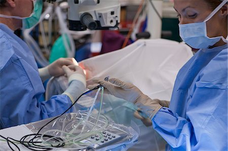 simsearch:6105-05396752,k - Surgical technologist passing a phaco hand piece to doctor during cataract surgery Foto de stock - Sin royalties Premium, Código: 6105-05396742