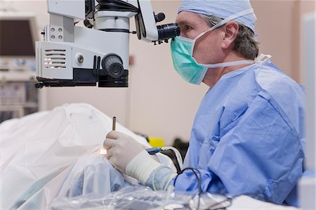 eye doctor - Médecin à la recherche au microscope à l'aide d'une pièce à main instrument et phaco cracker pendant la chirurgie de la cataracte Photographie de stock - Premium Libres de Droits, Code: 6105-05396750