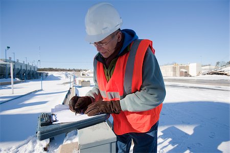 plymouth - Ingénieur, prendre des notes sur un presse-papiers électronique dans un parc industriel en hiver Photographie de stock - Premium Libres de Droits, Code: 6105-05396847