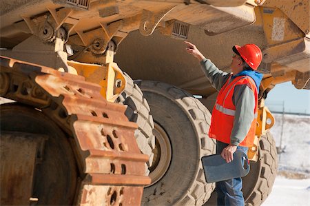 Engineer inspecting safety lights of earth mover Stock Photo - Premium Royalty-Free, Code: 6105-05396883