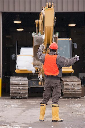 Transportation engineer directing an earth mover into a garage bay Stock Photo - Premium Royalty-Free, Code: 6105-05396950