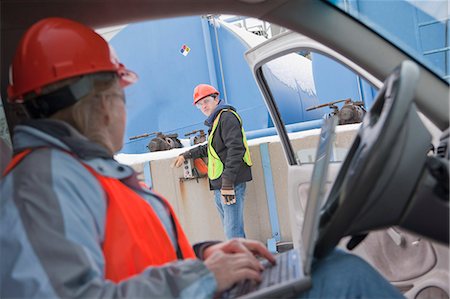 Engineer using a laptop in truck with an another engineer inspecting site Foto de stock - Sin royalties Premium, Código: 6105-05396970