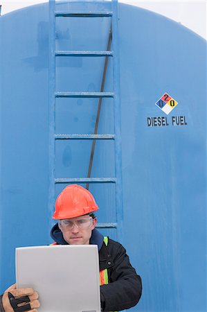 engineer with a ladder - Engineer recording data on a laptop near a fuel tanker Stock Photo - Premium Royalty-Free, Code: 6105-05396977