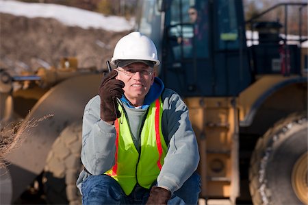 simsearch:6105-05396876,k - Engineer talking on a walkie-talkie directing front end loader at a construction site Stock Photo - Premium Royalty-Free, Code: 6105-05396904