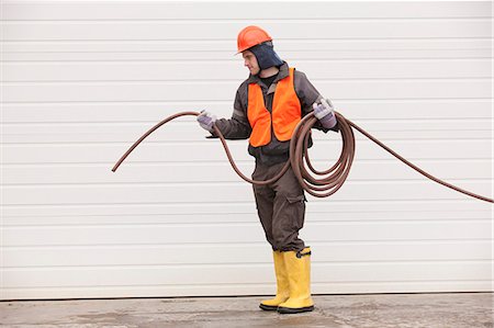 simsearch:6105-05396936,k - Transportation engineer pulling a hose at industrial garage Foto de stock - Sin royalties Premium, Código: 6105-05396932