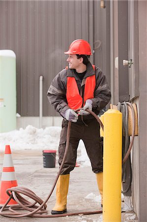 simsearch:6105-05396936,k - Transportation engineer reeling a hose at industrial garage Foto de stock - Sin royalties Premium, Código: 6105-05396936