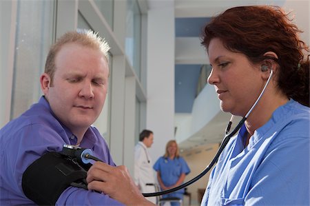 patient doctors group - Female nurse measuring a patient's blood pressure Stock Photo - Premium Royalty-Free, Code: 6105-05397044