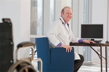 simsearch:6105-05397029,k - Doctor sitting in front of a computer and smiling Foto de stock - Royalty Free Premium, Número: 6105-05397023
