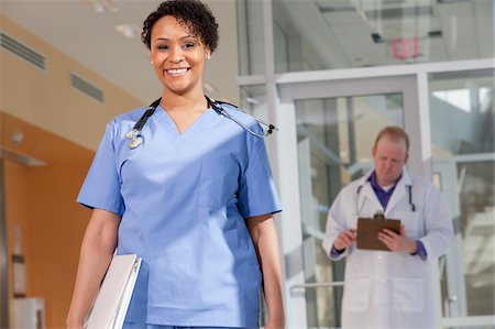 Portrait of a female nurse smiling with a male doctor standing behind her Stock Photo - Premium Royalty-Free, Code: 6105-05397020