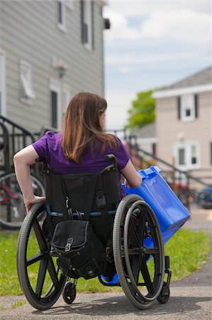 Woman with Spina Bifida in a wheelchair picking up a recycling bin at the street Stock Photo - Premium Royalty-Free, Code: 6105-05397273