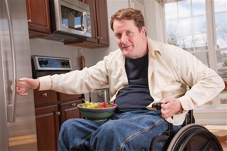 person in wheelchair at home - Man with spinal cord injury in a wheelchair getting bowl of fresh fruits from refrigerator Foto de stock - Sin royalties Premium, Código: 6105-05953682