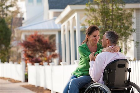 Couple enjoying each other's company in front of their home while he is in a wheelchair Foto de stock - Sin royalties Premium, Código: 6105-06042943