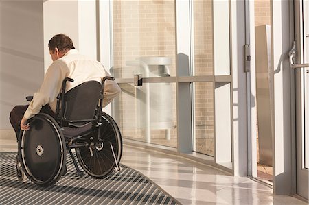 disability office - Businessman with spinal cord injury in wheelchair in a office building entrance Foto de stock - Sin royalties Premium, Código: 6105-06042948