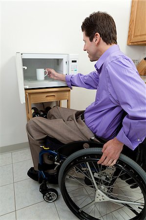 Man in wheelchair with spinal cord injury removing cup from an accessible microwave Foto de stock - Sin royalties Premium, Código: 6105-06042959