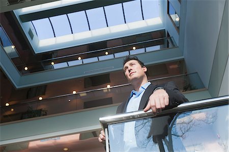 Businessman standing on the stairwell of an office building atrium Stock Photo - Premium Royalty-Free, Code: 6105-06043088