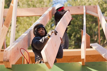 simsearch:6105-05396232,k - Carpenters placing roof rafter into position Stock Photo - Premium Royalty-Free, Code: 6105-06043013