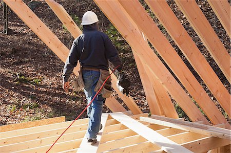 Carpenter with a nail gun at roof level Stock Photo - Premium Royalty-Free, Code: 6105-06043017