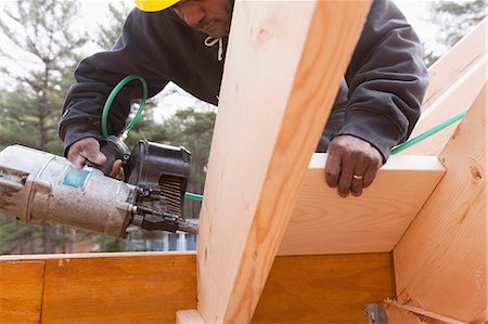 simsearch:6105-06043025,k - Carpenter with a nail gun on rafter braces Foto de stock - Sin royalties Premium, Código: 6105-06702848