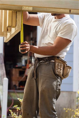simsearch:6105-06702940,k - Hispanic carpenter measuring rim joist for deck construction Stock Photo - Premium Royalty-Free, Code: 6105-06702904