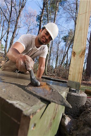 Hispanic carpenter using trowel to smooth concrete for staircase footing Stock Photo - Premium Royalty-Free, Code: 6105-06702911