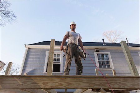 Hispanic carpenter using nail gun on home deck construction Foto de stock - Sin royalties Premium, Código: 6105-06702920