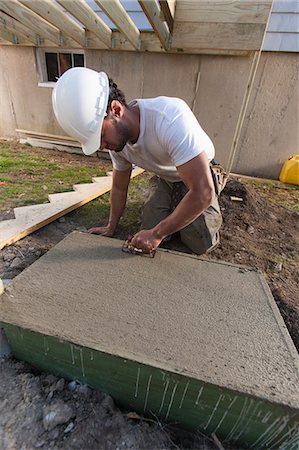 Hispanic carpenter using finish trowel to roughen stairway footing concrete Stock Photo - Premium Royalty-Free, Code: 6105-06702922