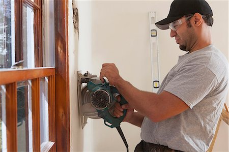 simsearch:6105-06702954,k - Hispanic carpenter using circular saw to cut wallboard for deck doorway in house Stock Photo - Premium Royalty-Free, Code: 6105-06702937