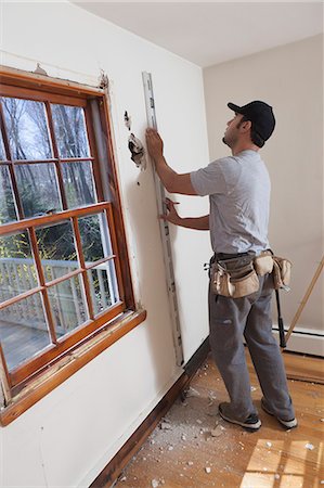 Hispanic carpenter using level to mark cut for new deck doorway in house Stock Photo - Premium Royalty-Free, Code: 6105-06702935