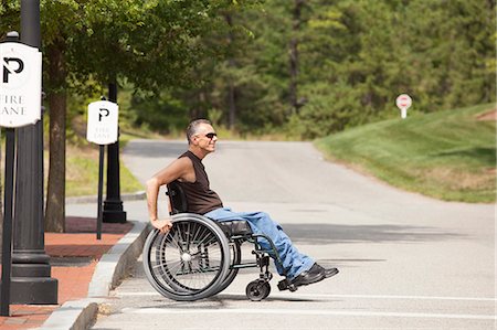 simsearch:6105-08211353,k - Man with spinal cord injury in a wheelchair crossing at accessible street walk Fotografie stock - Premium Royalty-Free, Codice: 6105-06703050