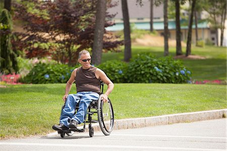 simsearch:6105-05396581,k - Man with spinal cord injury in a wheelchair crossing at accessible street walk Photographie de stock - Premium Libres de Droits, Code: 6105-06703051