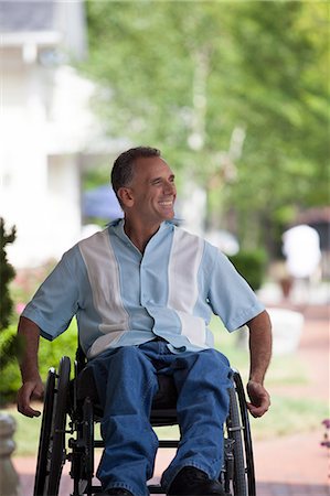 Man with spinal cord injury in a wheelchair enjoying outdoors Stock Photo - Premium Royalty-Free, Code: 6105-06703054