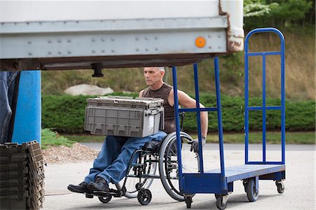 simsearch:6105-07744367,k - Loading dock worker with spinal cord injury in a wheelchair moving stacked inventory trays Foto de stock - Sin royalties Premium, Código: 6105-06703064