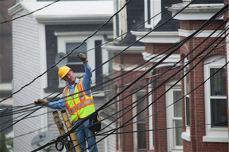 powerline - Cable lineman stretching a cable in the city from ladder Foto de stock - Sin royalties Premium, Código: 6105-07521240