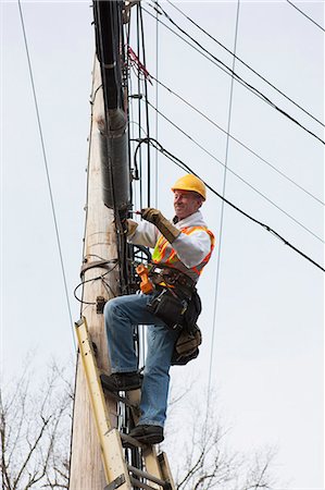 simsearch:6105-07521269,k - Communications worker attaching clamps to new cable bundle on power pole Stock Photo - Premium Royalty-Free, Code: 6105-07521265