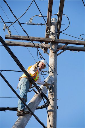 simsearch:6105-05396624,k - Cable lineman installing new suspension wire from power pole brace Stock Photo - Premium Royalty-Free, Code: 6105-07521282